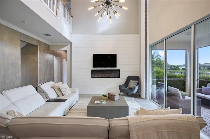 Living room with a towering ceiling, wooden walls, and an inviting chandelier