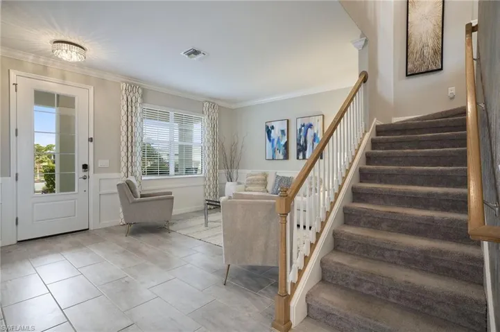 Foyer entrance featuring crown molding and light tile patterned floors