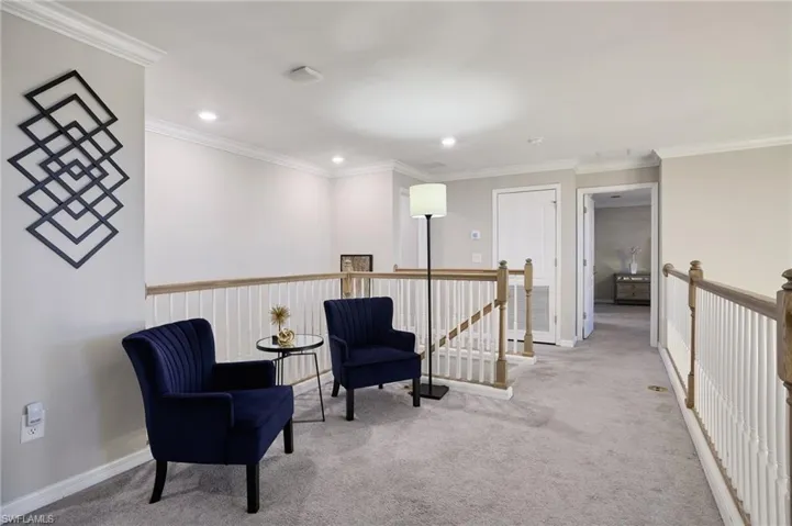 Living area featuring light colored carpet and crown molding