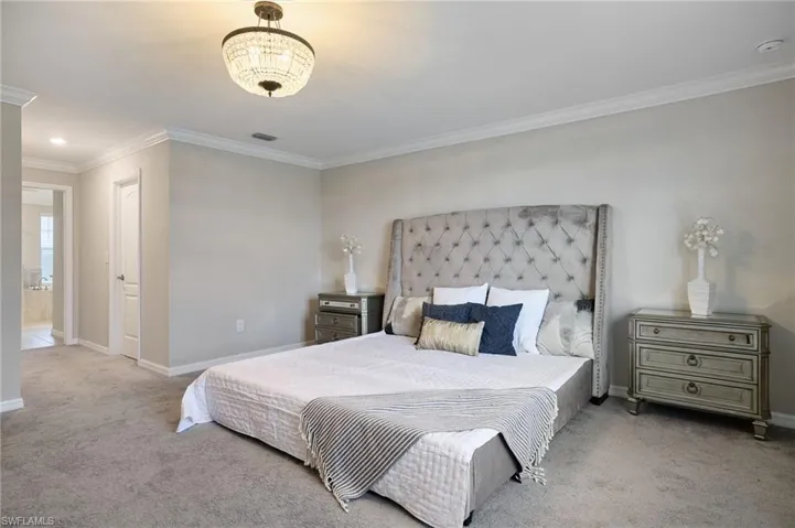 Carpeted bedroom with ensuite bathroom and ornamental molding