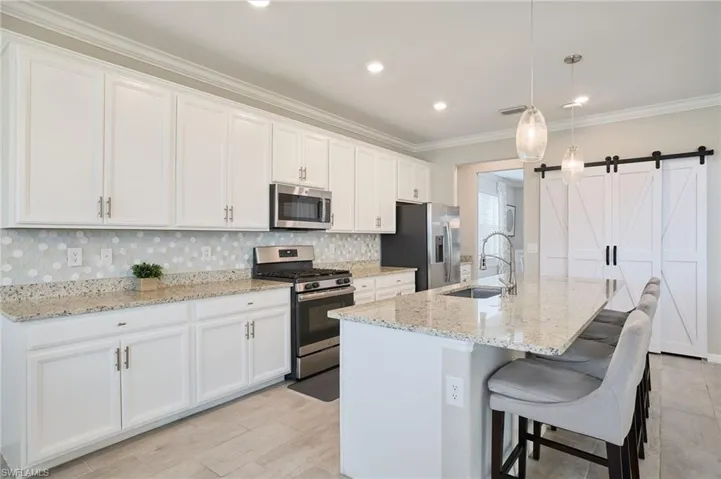 Kitchen with sink, white cabinetry, a kitchen island with sink, and appliances with stainless steel finishes