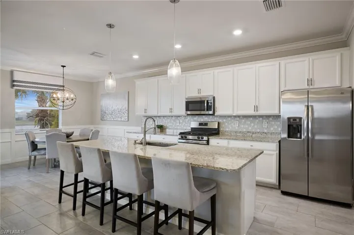 Kitchen featuring sink, a center island with sink, white cabinetry, and appliances with stainless steel finishes