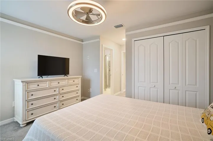 Bedroom with a closet, ornamental molding, and light carpet