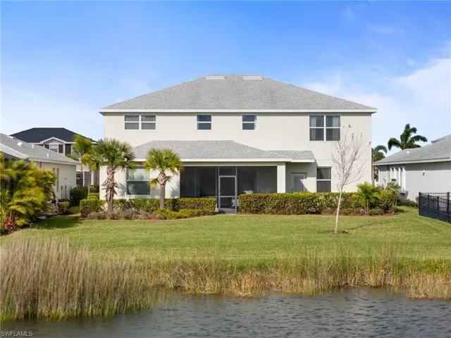Rear view of house with a sunroom, a lawn, and a water view