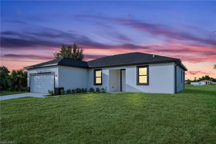 View of front of property with a garage and a lawn
