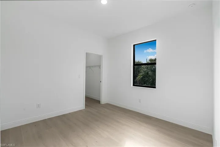Unfurnished bedroom with a spacious closet, light hardwood / wood-style flooring, and a closet