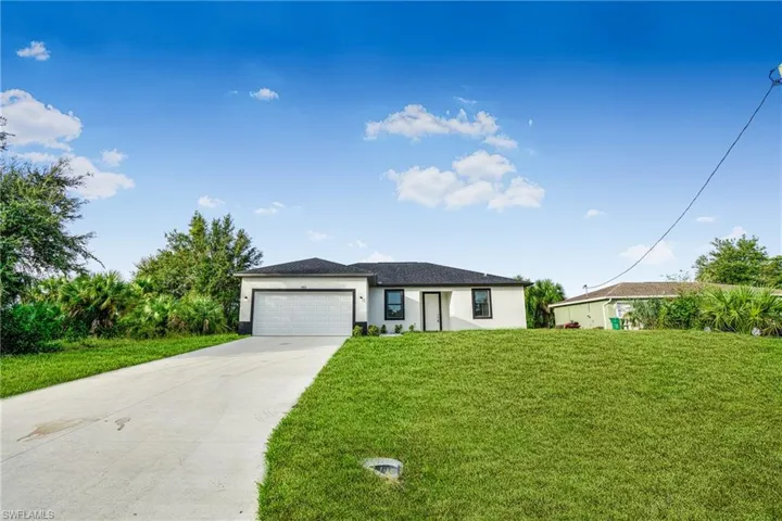 View of front of property featuring a front yard and a garage