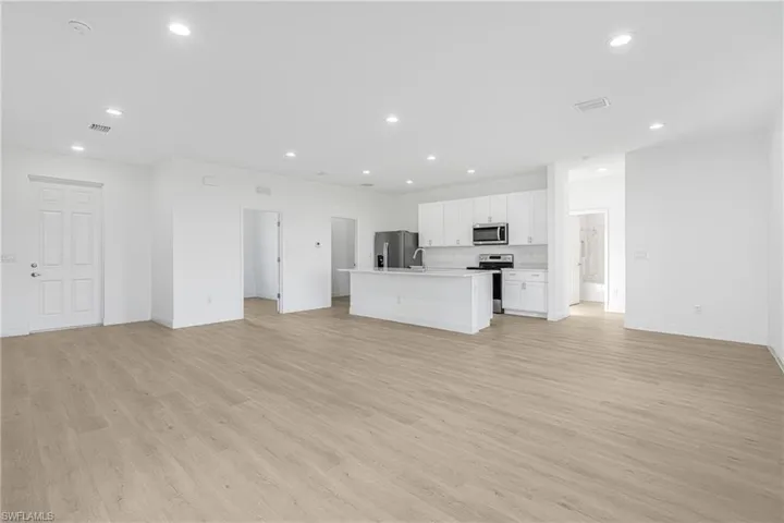 Unfurnished living room featuring sink and light hardwood / wood-style floors