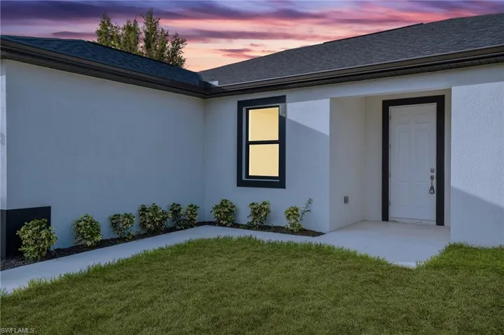 Exterior entry at dusk featuring a lawn