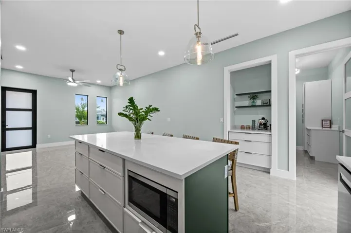 Spacious open-concept room featuring a large kitchen island with a white countertop and integrated microwave