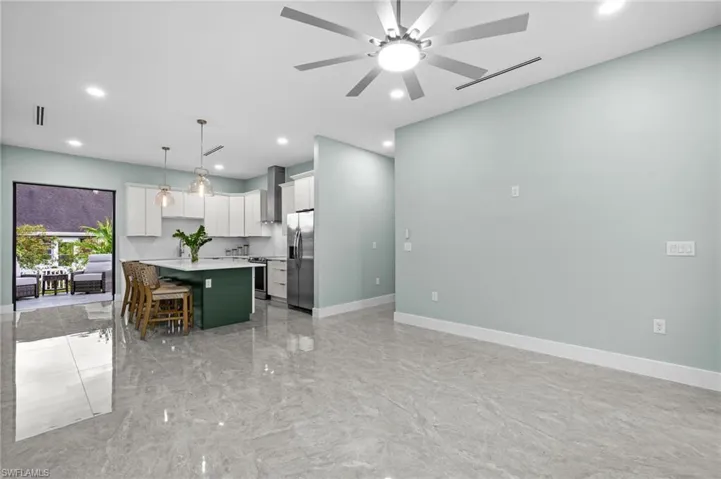 Open-concept living space with large format tile flooring and a ceiling fan