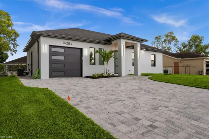 Contemporary exterior featuring a paver driveway, an attached garage with translucent paneling, and an inviting covered entry