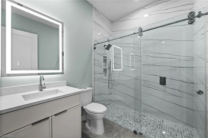 Bathroom featuring a contemporary floating vanity with an integrated sink, illuminated mirror, and a frameless glass shower with a sliding door