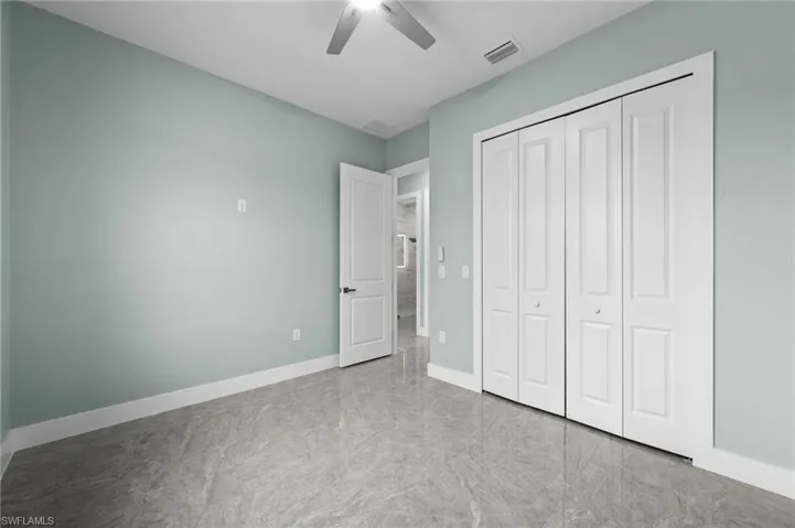Spacious room featuring light-colored walls, tile flooring, and a ceiling fan