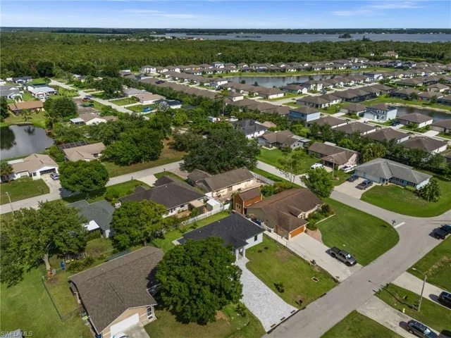 Aerial perspective showcasing a residential community with numerous single-story homes, many featuring private driveways and attached garages