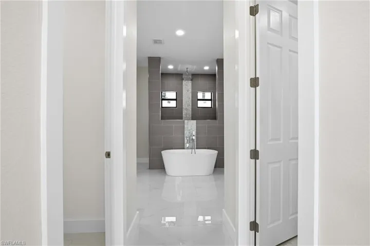 Bathroom with tile walls, a freestanding bath, and recessed lighting