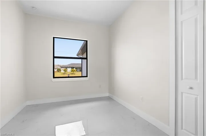 Unfurnished room featuring light marble finish flooring and baseboards