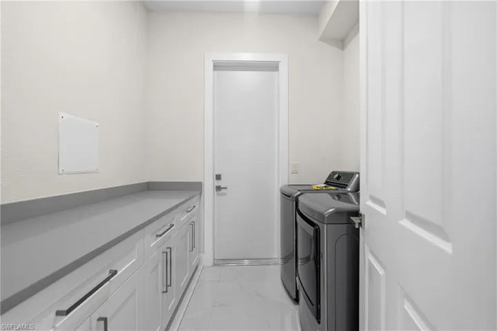 Laundry area with light marble finish flooring and washer and dryer