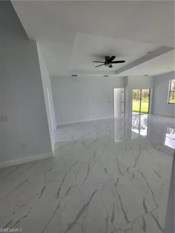 Unfurnished room with ceiling fan and a tray ceiling
