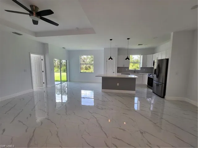 Kitchen with white cabinetry, a healthy amount of sunlight, appliances with stainless steel finishes, and a kitchen island