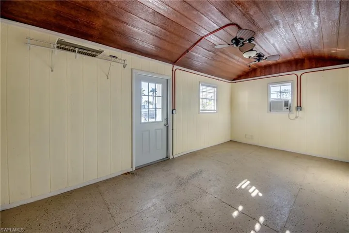 Garage with cooling unit, ceiling fan, wood walls, and wooden ceiling