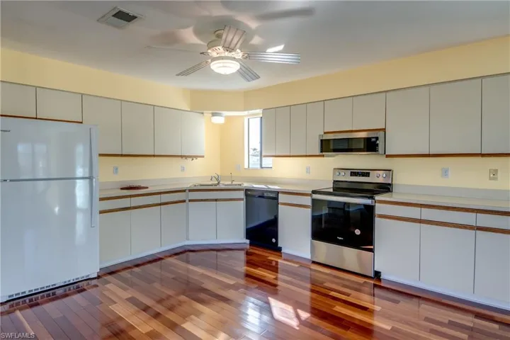 Kitchen with sink, ceiling fan, stainless steel appliances, white cabinets, and light wood-type flooring