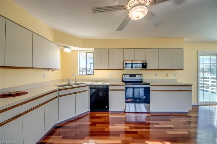 Kitchen featuring sink, stainless steel appliances, dark hardwood / wood-style floors, and white cabinets