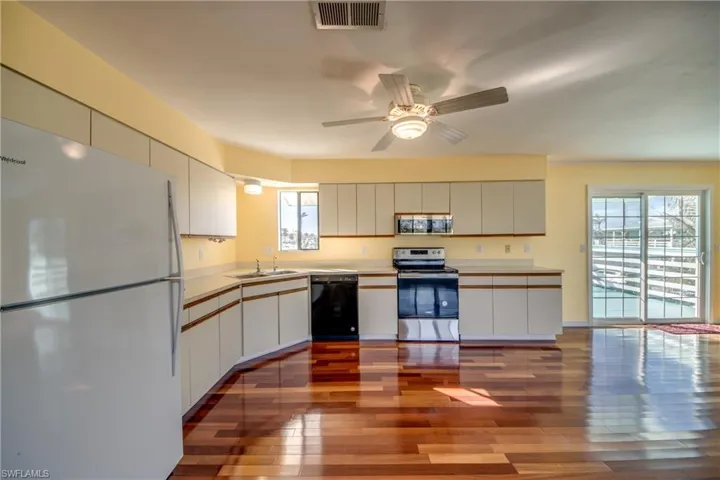 Kitchen with stainless steel appliances, light hardwood / wood-style floors, and white cabinets