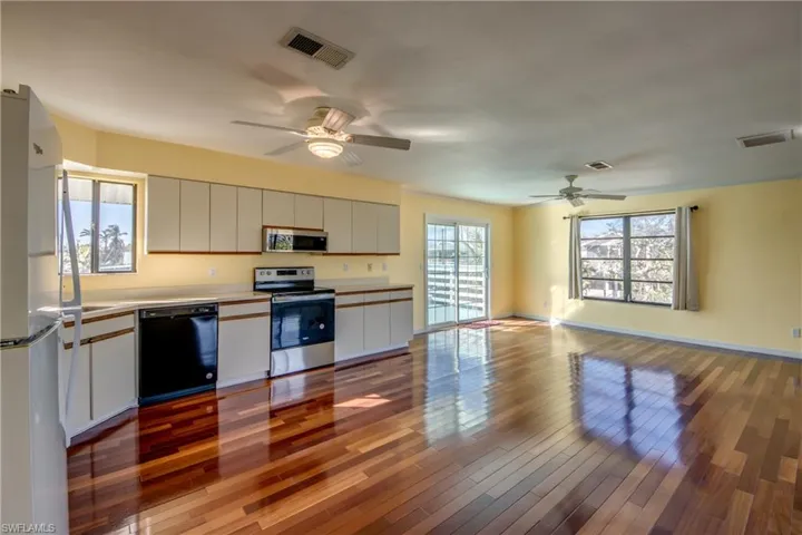 Kitchen with white cabinetry, ceiling fan, appliances with stainless steel finishes, and light hardwood / wood-style floors