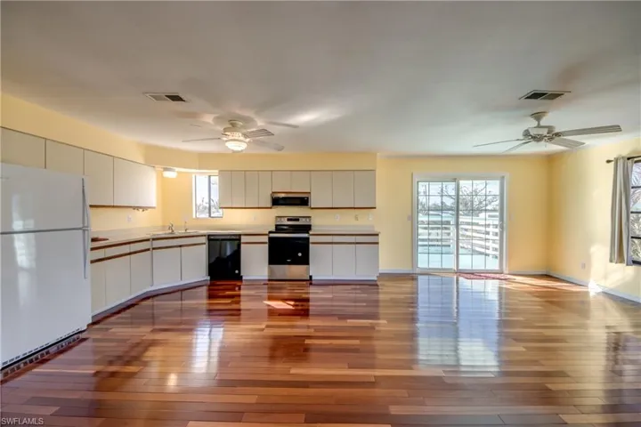 Kitchen featuring sink, light hardwood / wood-style flooring, appliances with stainless steel finishes, ceiling fan, and white cabinets