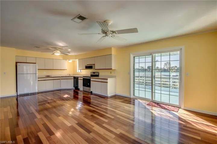 Kitchen with sink, white cabinetry, ceiling fan, stainless steel appliances, and light hardwood / wood-style floors
