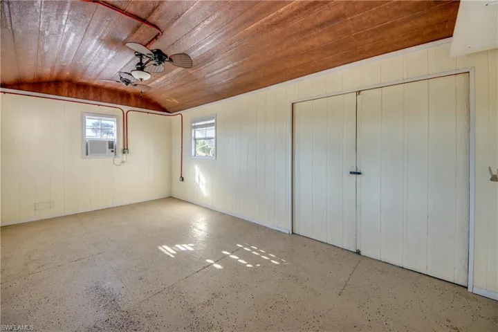 Unfurnished bedroom with vaulted ceiling, cooling unit, wooden ceiling, and a closet