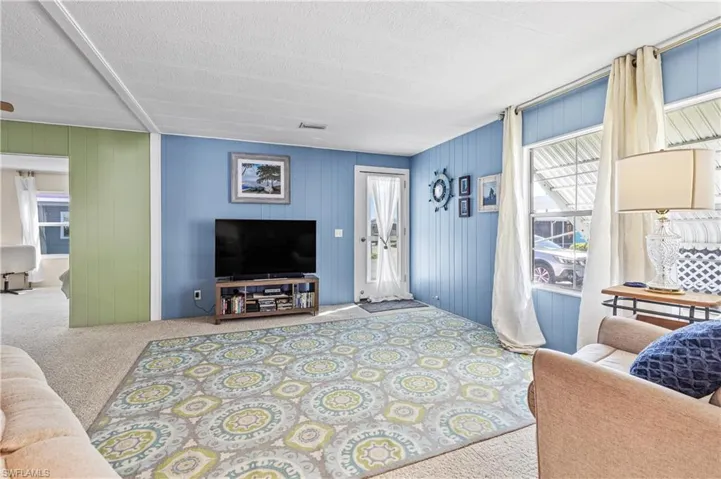 Living area with light colored carpet and wood walls