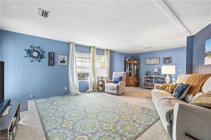 Living room with wooden walls, a textured ceiling, and carpet flooring