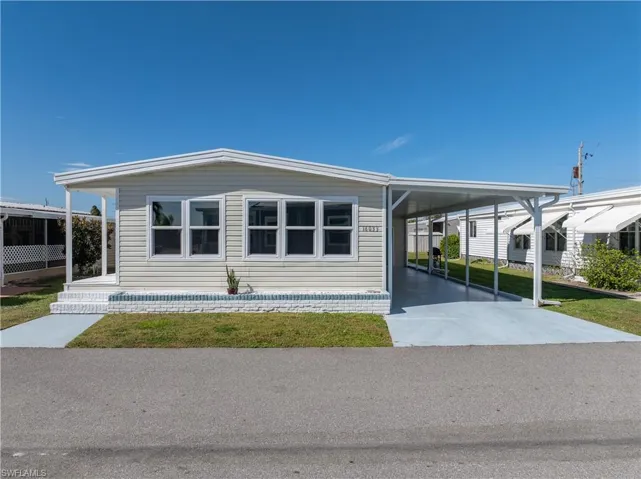 View of front of property featuring a carport, driveway, and a front yard
