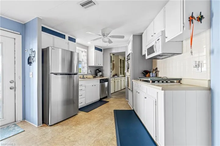 Kitchen featuring stainless steel appliances, light countertops, and white cabinetry