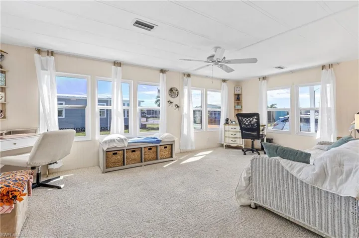 Carpeted bedroom with an office area, a ceiling fan, and wood walls