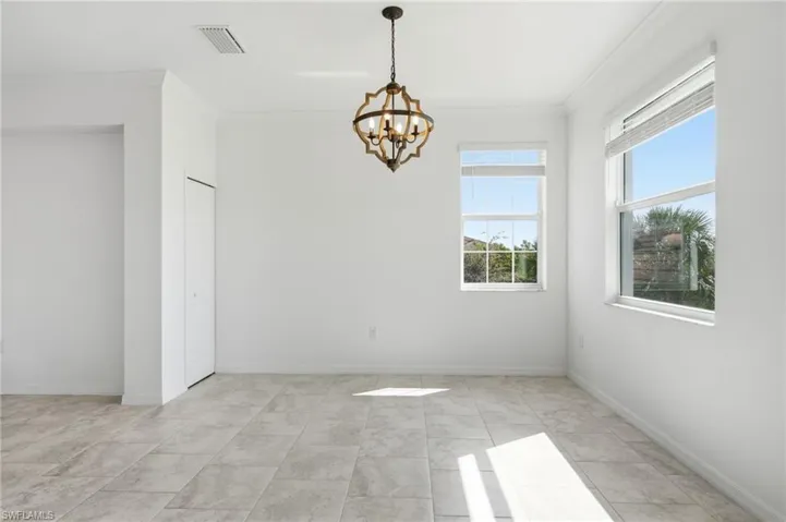 Neutral-toned tile flooring, geometric metal chandelier, and large windows with horizontal blinds