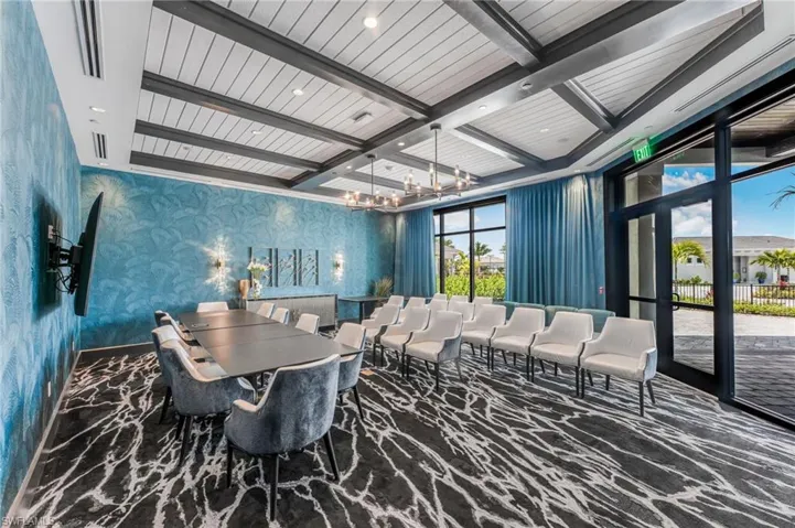 Coffered ceiling with dark timber beams and white shiplap detailing, dual tiered chandeliers, floor-to-ceiling glass wall, and integrated recessed lighting