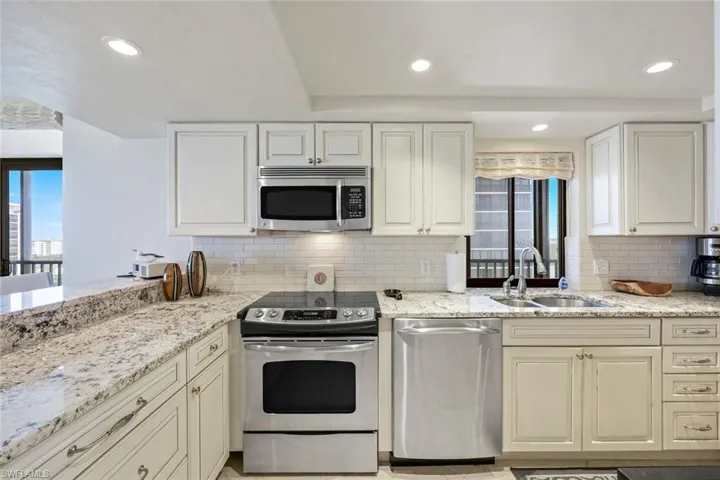 Kitchen with stainless steel appliances, light stone countertops, tasteful backsplash, recessed lighting, and white cabinets