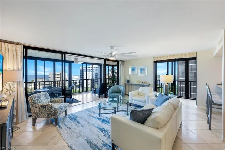 Living area featuring light tile patterned floors, ceiling fan, plenty of natural light, and a wall of windows
