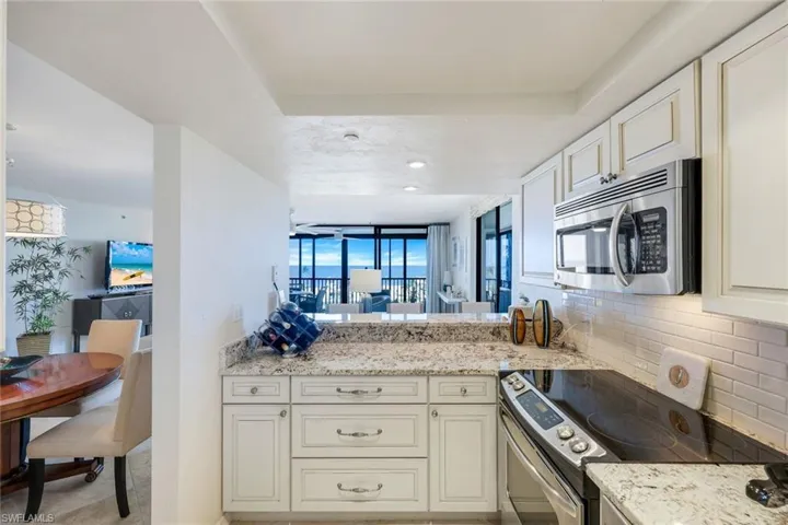 Kitchen with appliances with stainless steel finishes, tasteful backsplash, and light stone counters