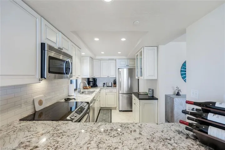 Kitchen with light stone counters, decorative backsplash, appliances with stainless steel finishes, light tile patterned floors, and recessed lighting