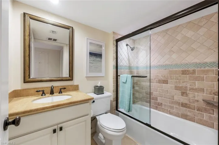 Bathroom featuring vanity and shower / bath combination with glass door