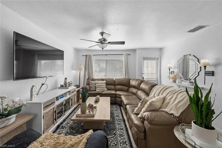 Living area featuring a textured ceiling, a textured wall, and a ceiling fan