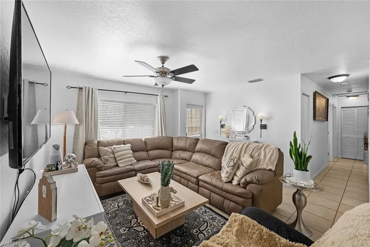 Living area featuring a textured ceiling, tile patterned flooring, and ceiling fan