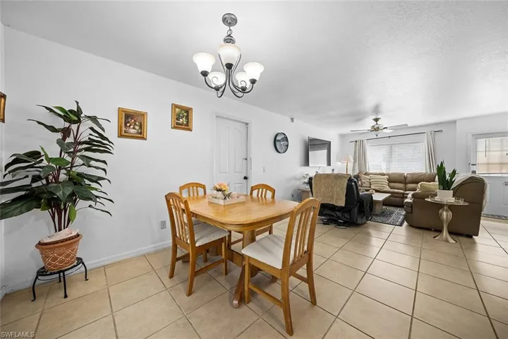 Dining room featuring a ceiling fan, light tile patterned flooring, a chandelier, and a textured ceiling