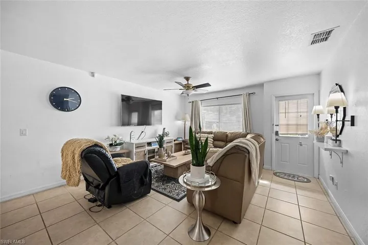 Living area featuring a textured ceiling, ceiling fan, and light tile patterned flooring