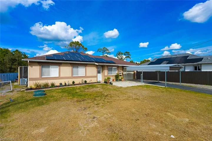 View of front of house featuring stucco siding, solar panels, and a detached carport