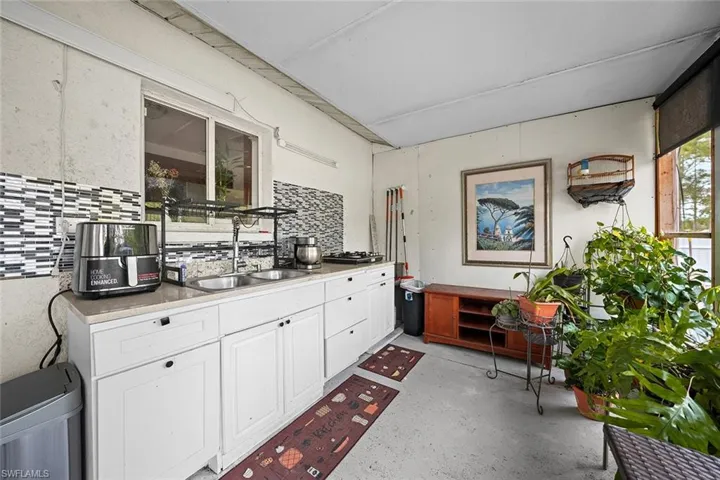 Kitchen featuring white cabinets, finished concrete flooring, and backsplash
